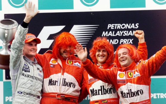 Com perucas, o diretor da Ferrari Ross Brawn e os pilotos Michael Schumacher e Rubens Barrichello comemoram o título da equipe em 2000