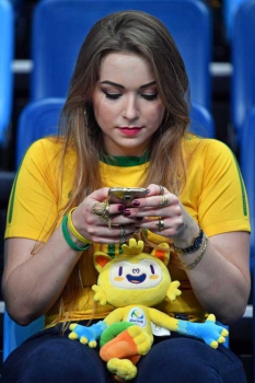 Brasileira usa seu celular durante jogo de basquete entre Brasil e Espanha