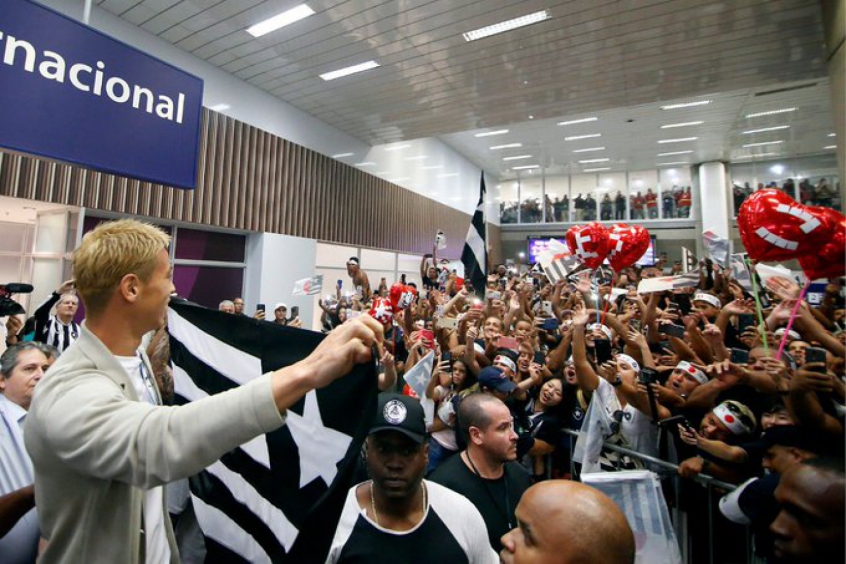 Keisuke Honda está em solos tupiniquins. O japonês, reforço do Botafogo para a temporada, desembarcou no Aeroporto Internacional Tom Jobim, o Galeão, na tarde desta sexta-feira e foi recebido com uma grande festa pela torcida do Alvinegro, que ocupou praticamente todo o setor do Portão D do Terminal 2 de saídas internacionais do estabelecimento. 