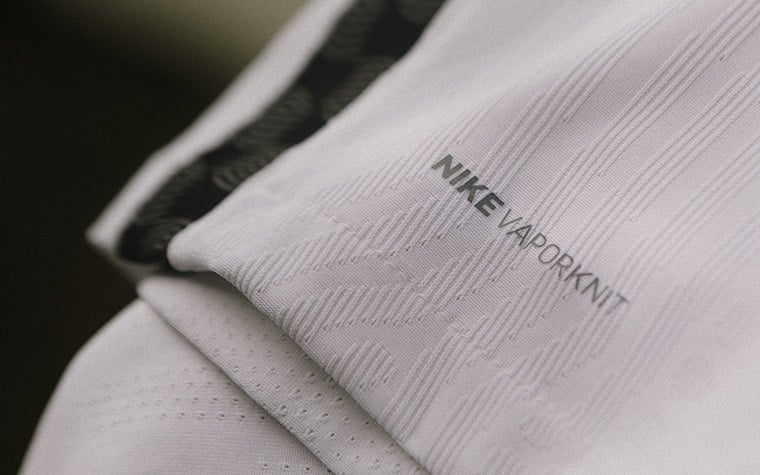 Detalhe da lista vertical lateral na cor preta e as informações do tecido fornecido pela Nike.