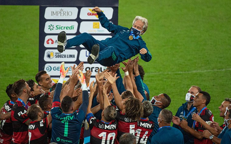 O ÚLTIMO TÍTULO - Flamengo comemora o caneco, mas sob clima de tensão (Foto: Reprodução SBT) Já em meio à polêmica de sua saída, Jorge Jesus vê o Flamengo bater o Fluminense no dia 15 de julho e conquistar o título carioca. Entretanto existia o clima de tensão pela saída do técnica. Mas a diretoria garantia a sua permanência.