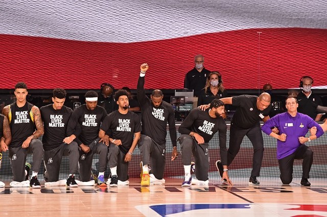 Jogadores do Los Angeles Lakers ajoelham-se minutos antes de entrarem em quadra diante do Los Angeles Clippers, prestando homenagem durante o hino dos EUA em apoio ao movimento Black Lives Matter (Vidas Negras Importam), na luta contra a brutalidade racial e injustiça social