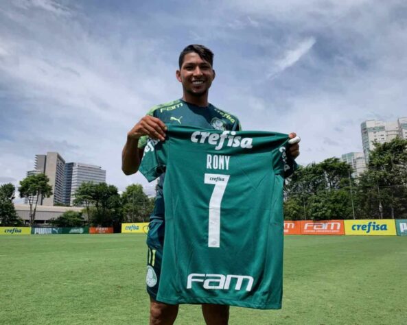 ESQUENTOU - O Palmeiras anunciou, na tarde desta segunda-feira (5), que o atacante Rony vai passar a usar a camisa 7 a partir da atual temporada. Simbólico na história do clube, o número estava ‘vago’ desde a saída de Dudu, na metade de 2020, e já pertenceu a ídolos como Paulo Nunes e Edmundo no passado. Agora, o ex-camisa 11, que foi um dos protagonistas da conquista da última Libertadores, assume este legado. A curiosa mudança ocorre em meio ao interesse de um gigante europeu em Rony: conforme noticiado pelo repórter André Hernan, do portal ‘ge’, o Ajax-HOL fez uma sondagem pelo atleta recentemente. Segundo apuração da reportagem do NOSSO PALESTRA/LANCE!, ainda não há iminência de uma proposta oficial e o Verdão trabalha com a ideia de seguir com o paraense em seu plantel.