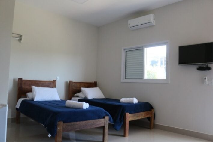 Dormitório com duas camas, ar condicionado e sistema de televisão.