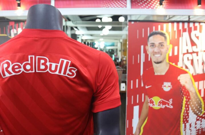 Loja do Red Bull Bragantino dá ênfase ao novo uniforme do clube, na cor vermelha. Ao fundo, o meia Praxedes posa com a nova camisa.