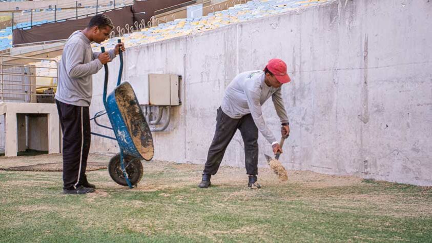 Trabalhadores seguem nos últimos preparativos e misturavam areia com a grama sintética do lado de fora do gramado de jogo.