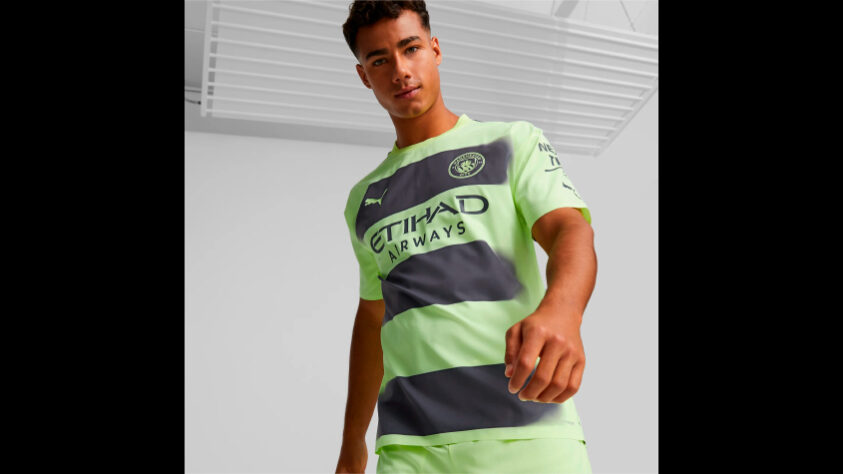 MANCHESTER CITY - A peça alternativa do Manchester City tem como base a cor verde neon que é acompanhada de faixas horizontais largas em azul marinho que somem em degrade próximo às laterais do manto. A inspiração é na “Manchester Worker Bee”, um dos símbolos da cidade.