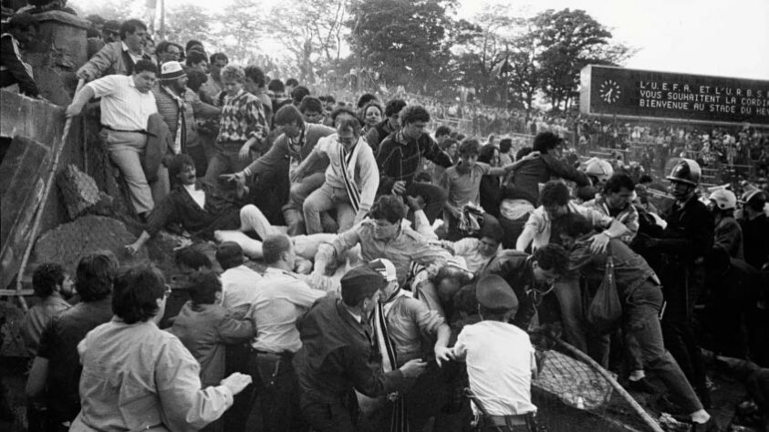 Em meio de 85, aconteceu a tragédia de Heysel, em Bruxelas, onde 39 pessoas morreram, pois, antes do jogo entre Liverpool e Juventus, os ingleses invadiram as arquibancadas onde estavam os torcedores italianos. Em meados de 1985, ocorreu a tragédia de Heysel, em Bruxelas. 39 pessoas faleceram no desastre, pois os ingleses invadiram as arquibancadas onde estavam os torcedores italianos. 