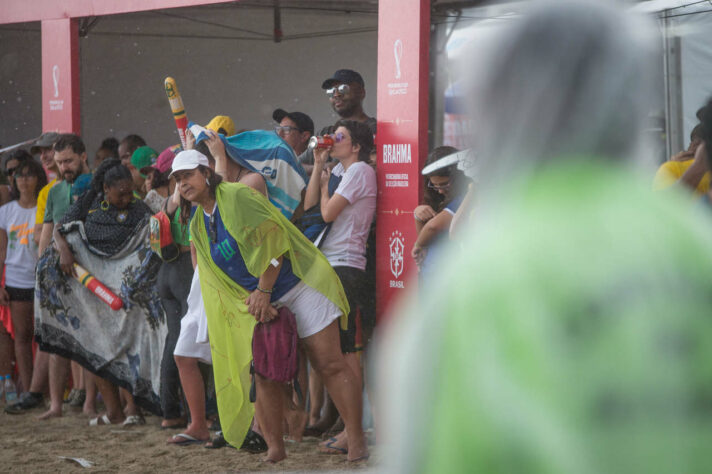 A torcedora dá uma espiadinha no jogo enquanto se protege da chuva.