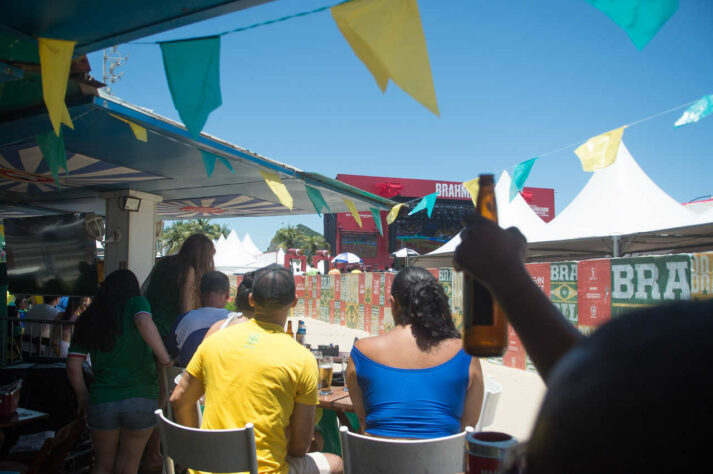 Torcedores se protegem do sol enquanto aguardam o início do jogo. 