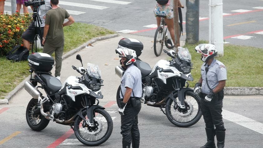 Polícias observam multidão nas ruas de Santos.
