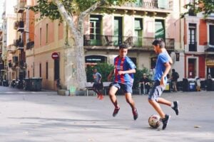 meninos jogando futebol na rua