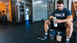 Homem tomando shake com albumina na academia