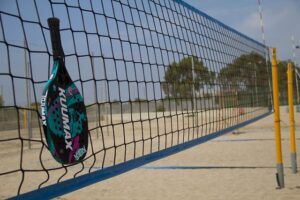 Raquete e rede de tênis na praia.