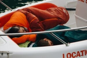 Pessoas dormindo em saco de dormir dentro do barco