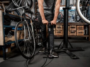 Homem enchendo pneu de bicicleta com bomba de ar.