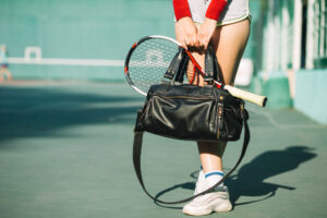 Mulher com bolsa e equipamento de tênis.